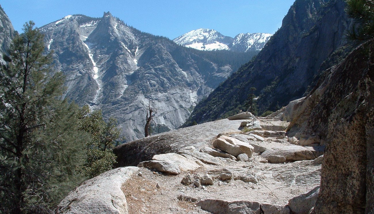 A trail with steps is carved in a mountain of white granite.