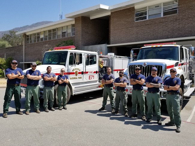 Firefighters pose in front of structural and wildland fire engines.