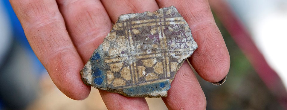 Archeologist holds ceramic sherd.