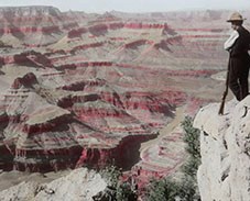 Man looking out at the Colorado River and Grand Canyon National Park, 1890s. Colored lantern slide.