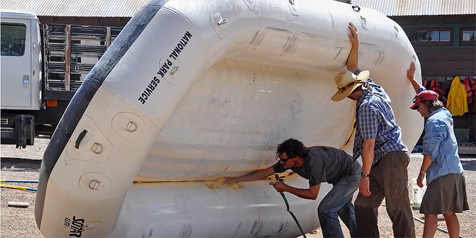 three employees clean off an inflatable boat