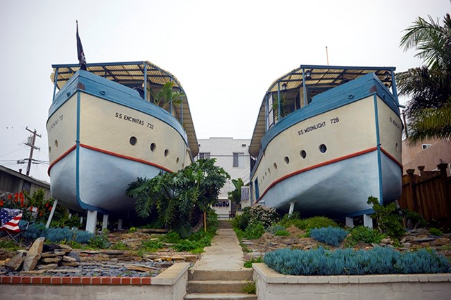 CA_San Diego_Encinitas Boathouses Image of two houses shaped like boats, with walkways, low walls, and plants.