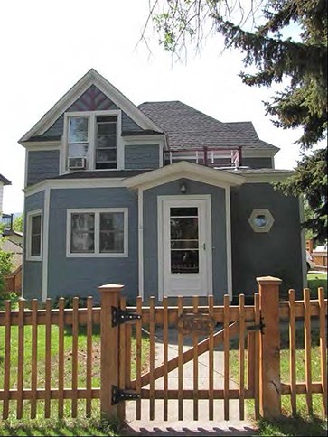 Image of two story blue house with fence.