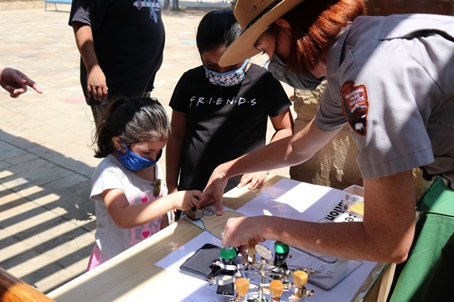 Park ranger helping kids stamp their passport book.