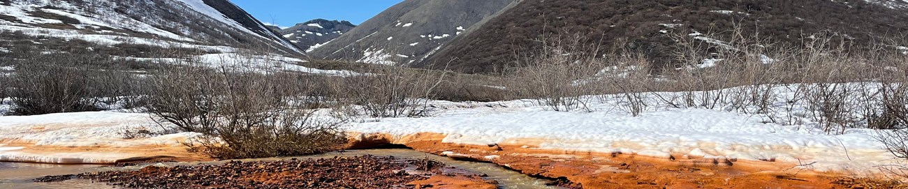 orange river with white snow and mountains and blue skies in background