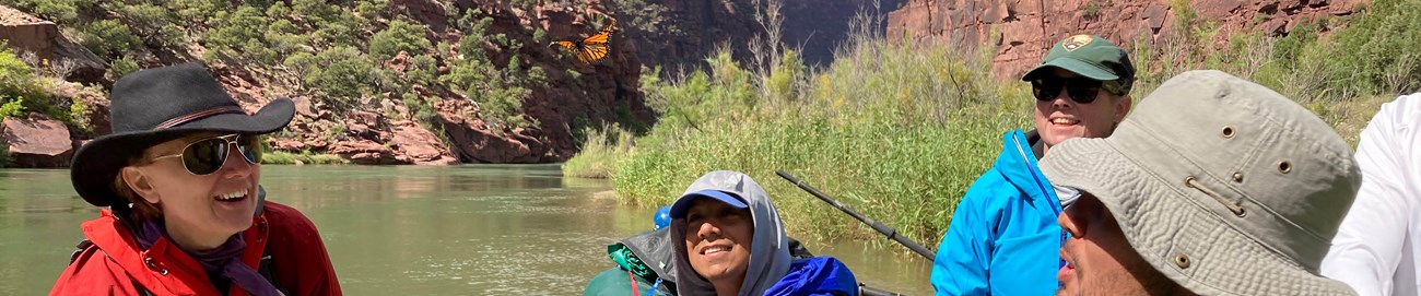 People in a river raft watch a released monarch butterfly fly away