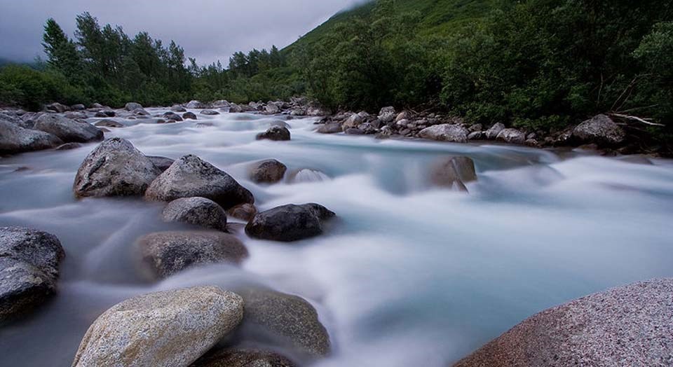 Flowing water moving over large tumbled boulders in the riverbed.