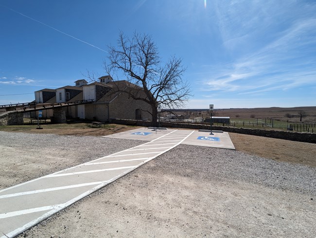 Two handicapped parking spaces next to large stone barn