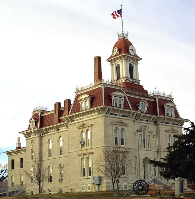 Chase County Courthouse, a large white stone-walled building with steep red roofs, a clock on top, and above all, an American flag.