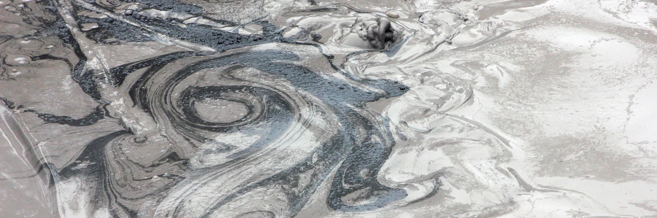 Swirling mud at Mud Volcano Swirls of black, gray, and white in a bubbling mudpot.