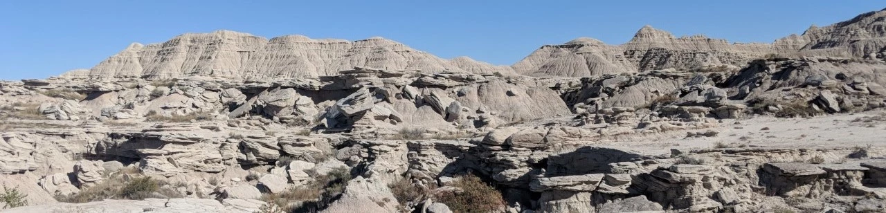 a vast landscape of eroded buttes, layered with more resistant sandstone boulders.