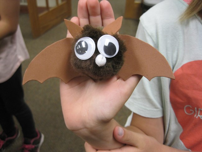 Child's hand holding a bat craft