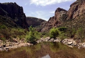 Fish Creek with small trees and rocky hillsides surrounding it.