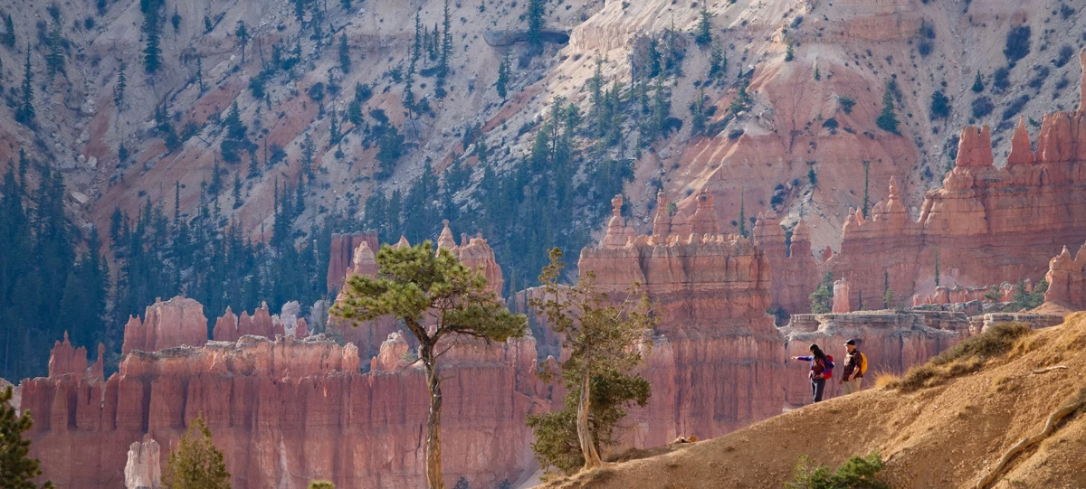 Amphitheater Hikes Banner Two hikers descend a trail surrounded by red rock formations