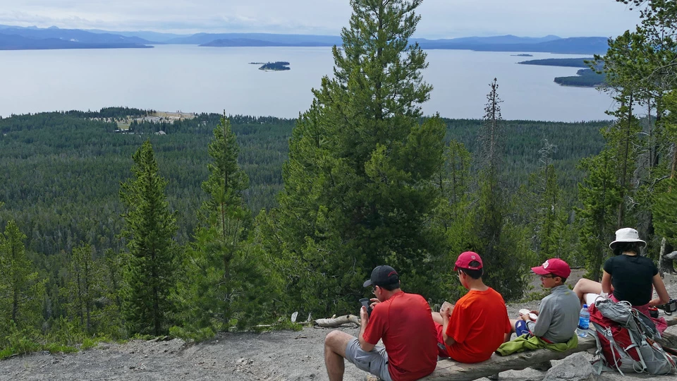 Hikers at the top of Elephant Back Mountain Hikers rest at the top of a mountain and look out at Yellowstone Lake