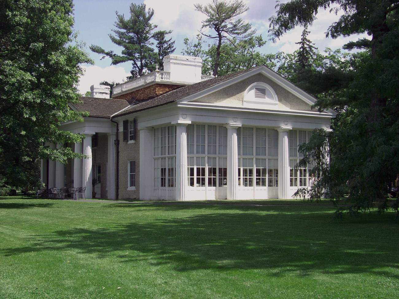 A classical building with central pedimented portico and captain's walk on the roof.