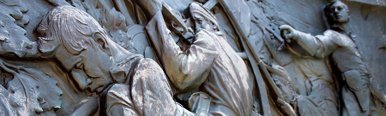 Relief sculpture on the Missouri State Memorial depicting one man standing over two other men in battle