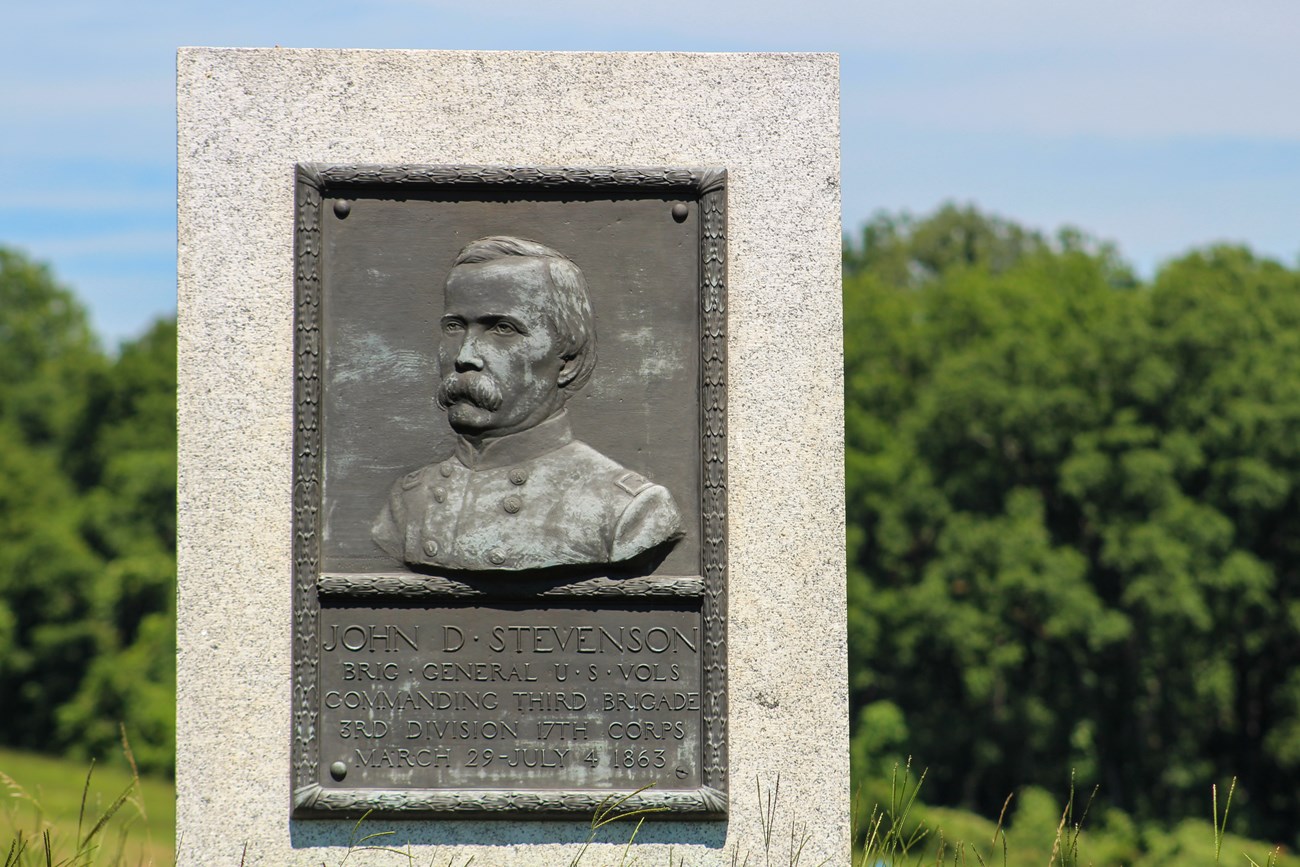 A bronze relief portrait of a man in uniform, under the portrait is a small plaque with a short inscription