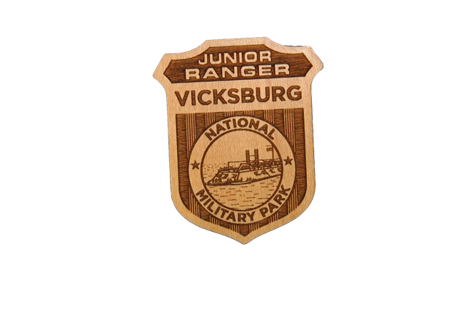 A wooden badge with an image of the USS Cairo in the middle. The badge reads Junior Ranger Vicksburg National Military Park