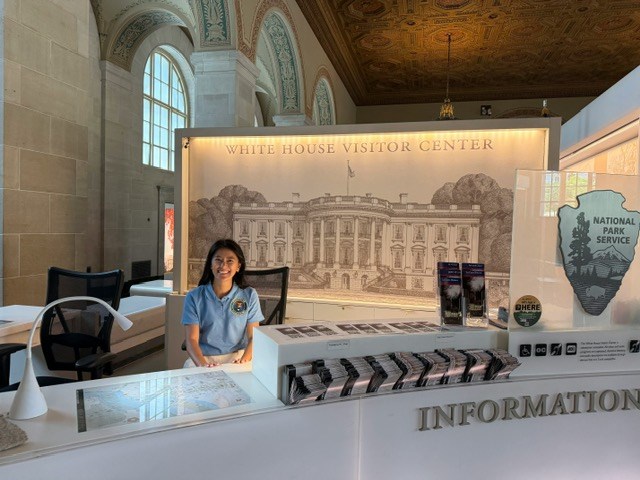 Smiling Volunteer seated at the White House Visitor Center Information Desk