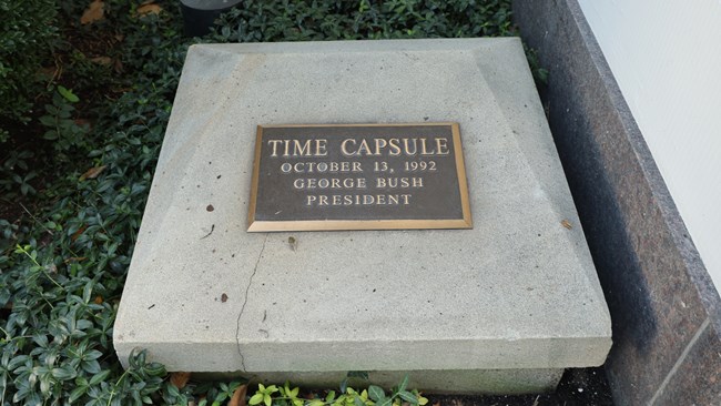 A bronze plaque says "Time Capsule October 13, 1992 George Bush President" atop a concrete square.
