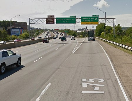 A green street sign above the highway