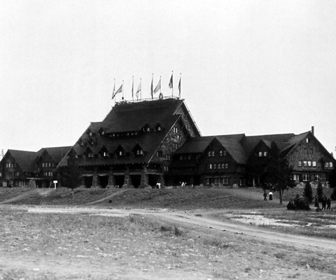 Black and white image of a log building with steep roods and flags on top