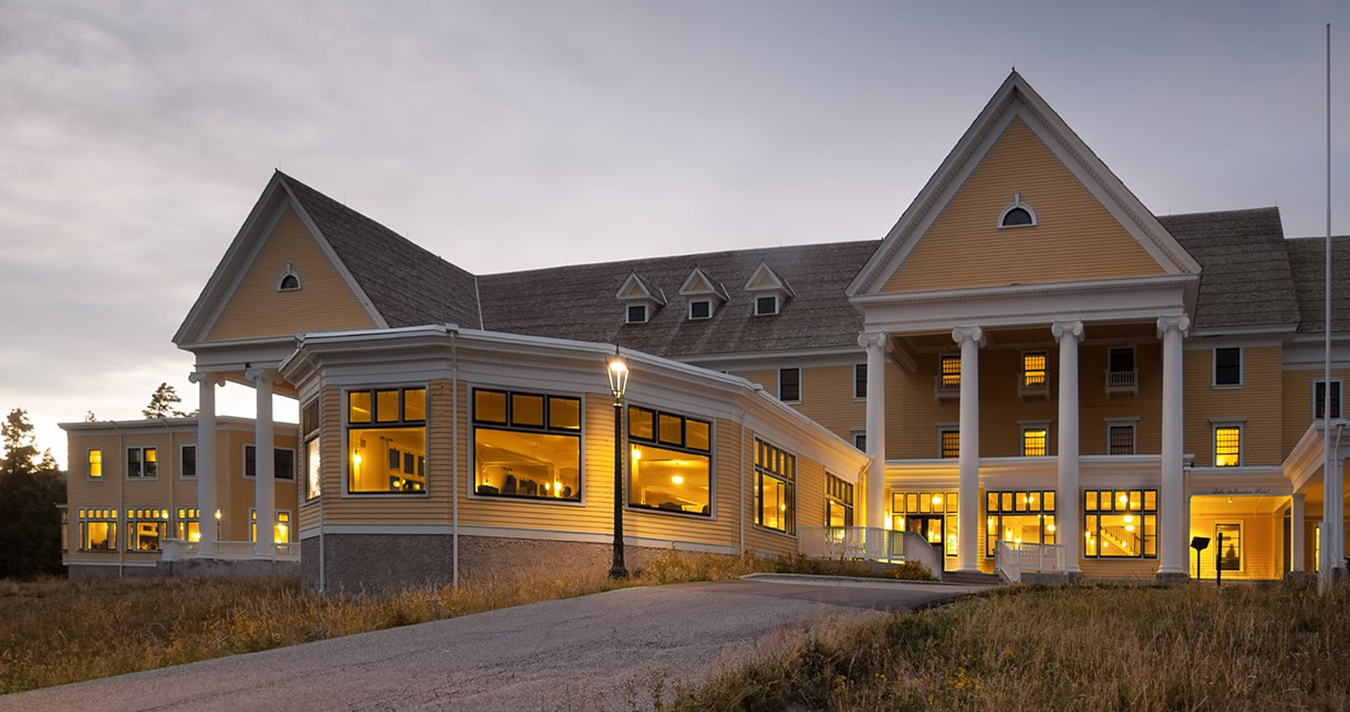 A large yellow building with many windows lit by interior lights.