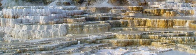 Dozens of flat terraces of white, yellow, and brown with water flowing through the area.