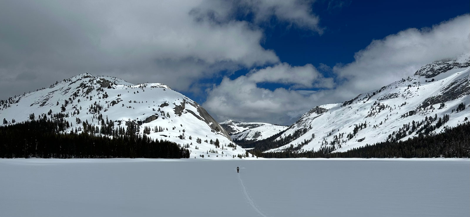 Tenaya Lake covered in snow with Pywiack Dome and other snowy peaks in the background