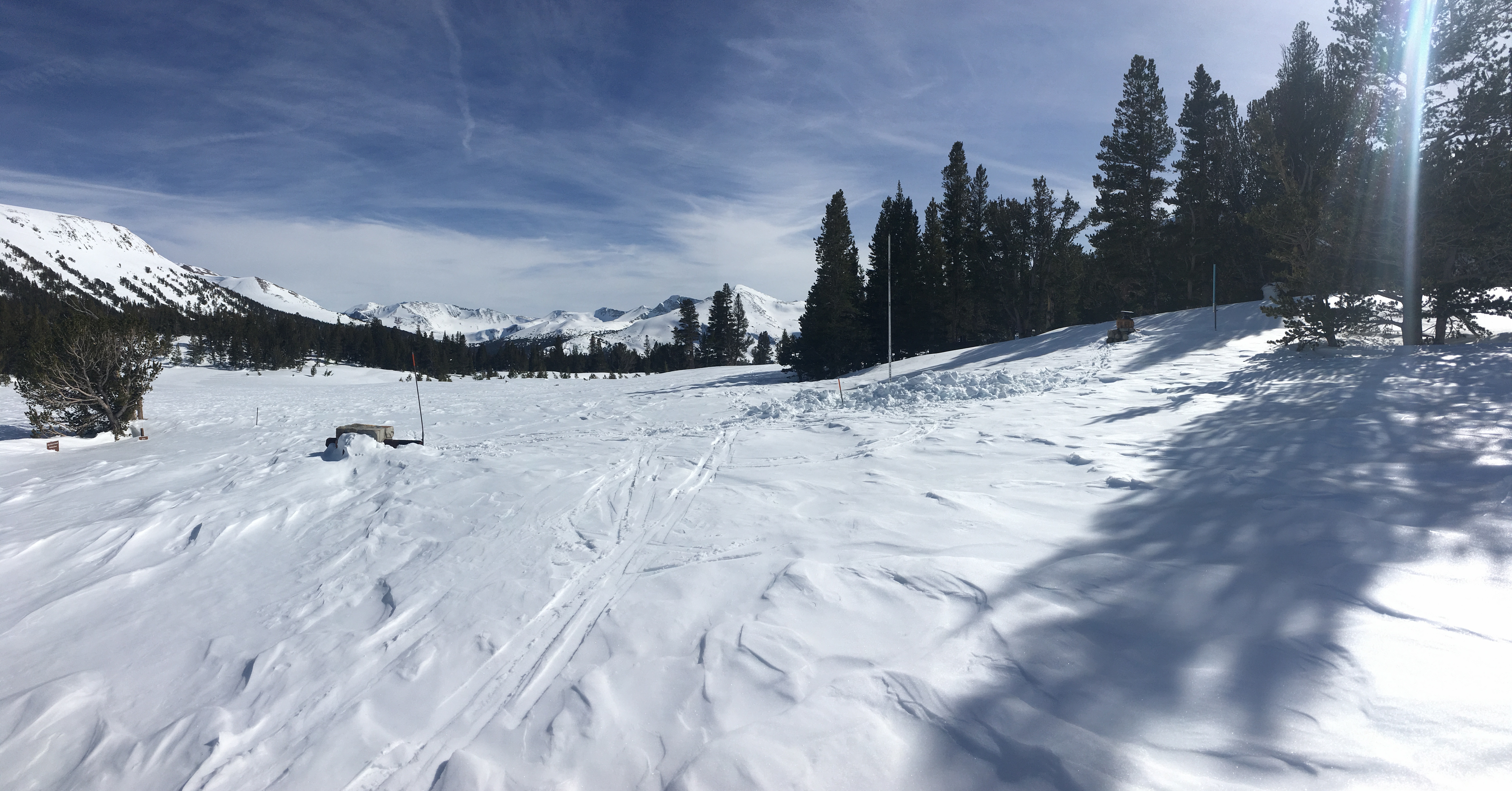 Photo of Tioga Pass Entrance, which is not visible because it's buried in snow; the very top of a stone signpost pokes up above the snow